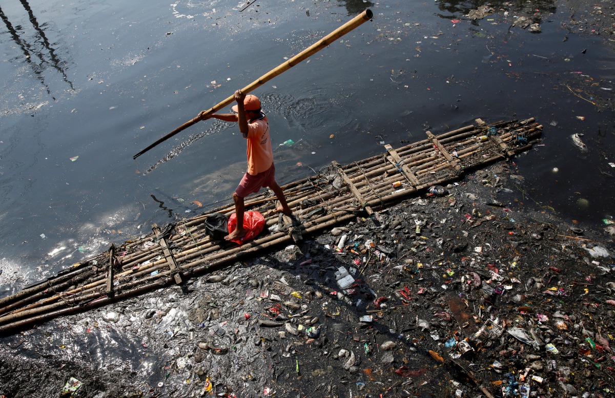 FILE PHOTO: A government worker uses a raft to gather plastic and other debris for collection and disposal from the Sekretaris River in Jakarta, Indonesia, June 7, 2017. Reuters/Darren Whiteside