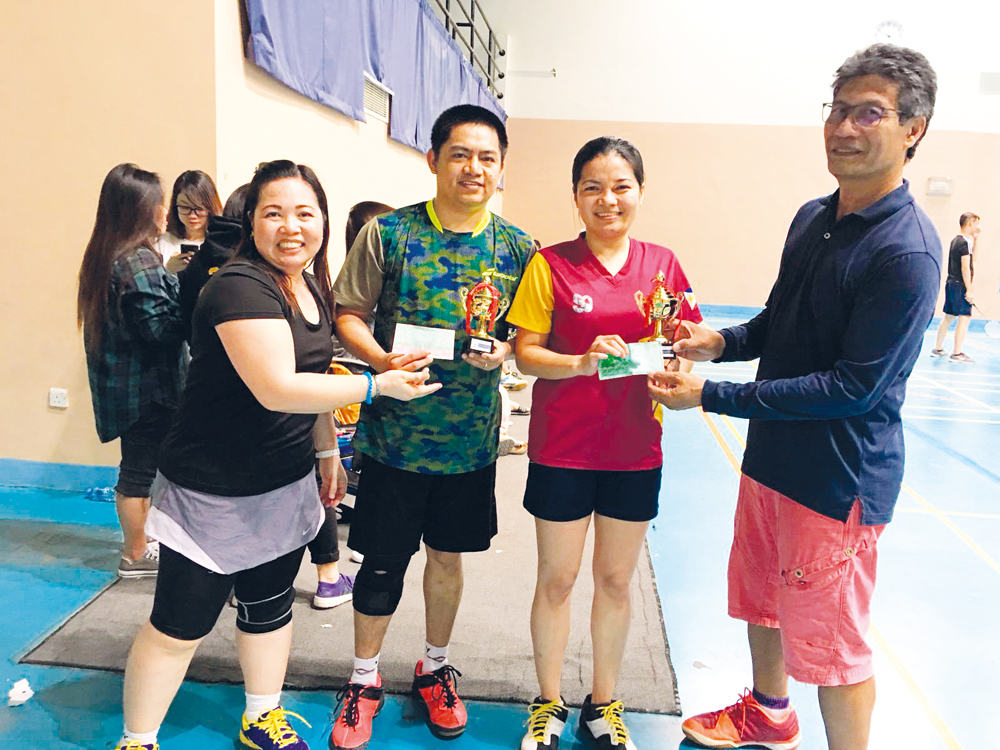 Mixed Doubles winner Raquel Bamba and Ryan Bamba, receiving the winner's trophy from Carmencita Ortiaga (left), President of Flickers Qatar and Renato Ajero (right), Founder of Flickers Qatar.