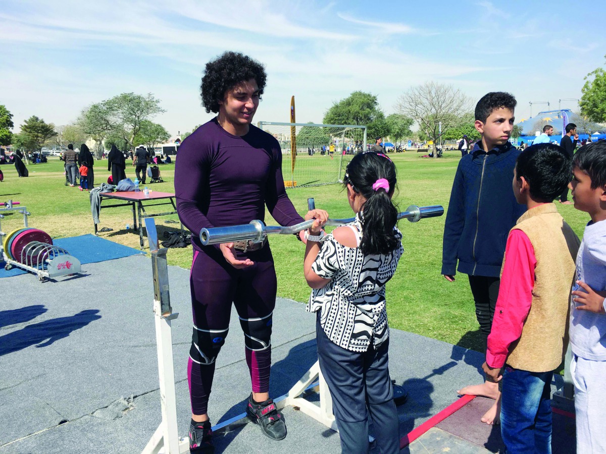 World junior champion Fares Ibrahim  offers tips to young weightlifters at the Team Qatar Village at Aspire Park yesterday.