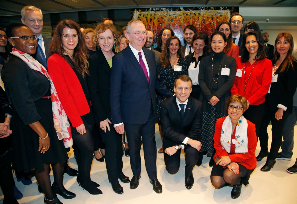 French President Emmanuel Macron (2ndR) and French Junior Minister for Gender Equality Marlene Schiappa (2ndL) pose with employees of an investment company where women and men are paid the same for the same work, on March 8, 2018 in Paris. AFP / Michel Eu