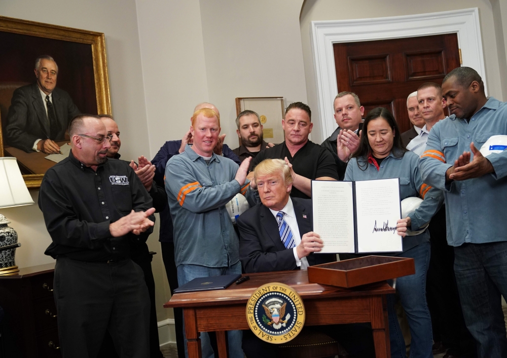US President Donald Trump shows his signature on Section 232 Proclamations on Steel and Aluminum Imports in the Oval Office of the White House on March 8, 2018, in Washington, DC. / AFP / MANDEL NGAN 