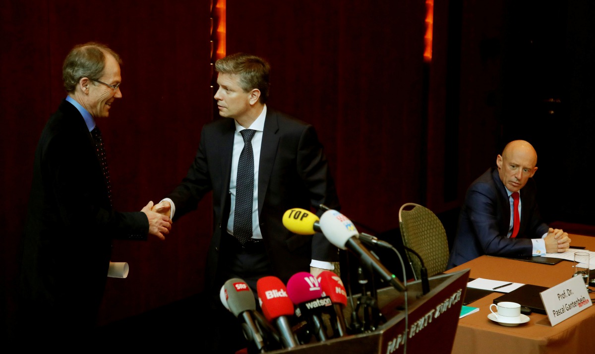 CEO Patrik Gisel (R) of Switzerland's third-largest bank Raiffeisen, looks on as interim chairman Pascal Gantenbein (C) and re-signed chairman Johannes Rueegg-Stuerm shake hands during a news conference in Zurich, Switzerland March 9, 2018. Reuters/Arnd W
