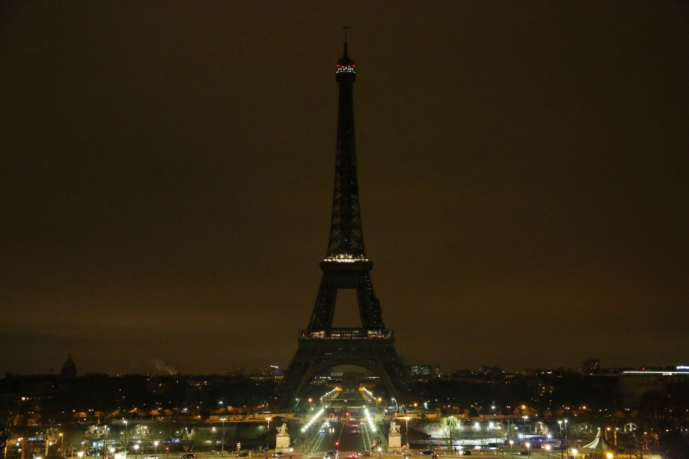 The lights of the Eiffel Tower are dimmed at midnight, March 23, 2018 in Paris to honor victims killed at a supermarket in southwest France by a man claiming allegiance to the Islamic State. AFP / Zakaria ABDELKAFI