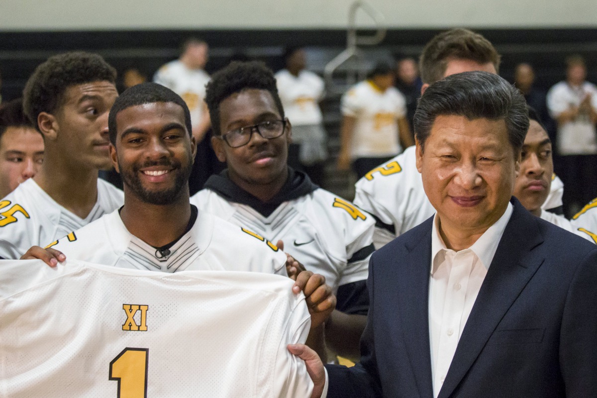 Chinese President Xi Jinping receives a football jersey bearing his name as he visits Lincoln High School in Tacoma, Washington. (Reuters) 