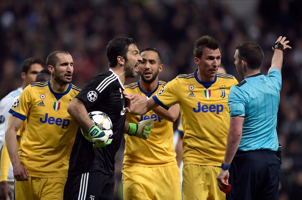 Juventus' Italian goalkeeper Gianluigi Buffon (2L) argues with the referee during the UEFA Champions League quarter-final second leg football match between Real Madrid CF and Juventus FC at the Santiago Bernabeu stadium in Madrid on April 11, 2018. / AFP 