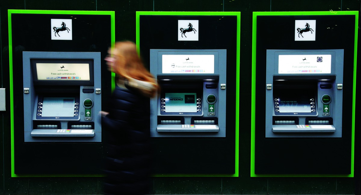 A woman walks past a row of cash machines outside a branch of Lloyds Bank in Manchester, Britain, February 21, 2017. Picture taken February 21, 2017. Reuters/Phil Noble