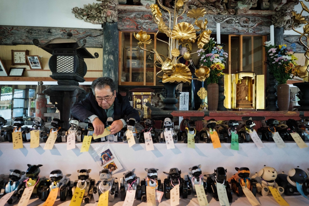 A man organises Sony's pet robot AIBOs on an altar prior to hold the robots' funeral at the Kofukuji temple in Isumi, Chiba on April 26, 2018. AFP / Nicolas Datiche