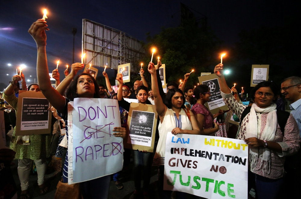 People hold candles and placards during a protest against the rape of an eight-year-old girl, in Kathua, near Jammu, a teenager in Unnao, Uttar Pradesh, and an eleven-year-old girl in Surat, Gujarat, in Ahmedabad, Indiia, April 16, 2018. Reuters/Amit Dave