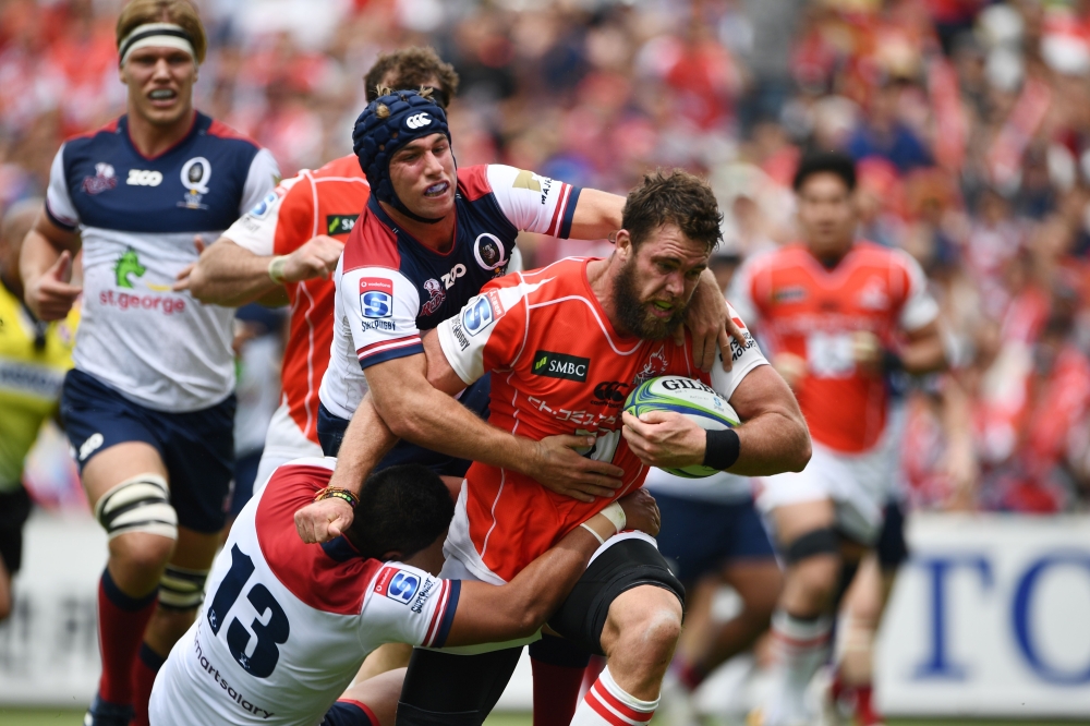 Sunwolves' lock Grant Hattingh (R) is tackled by Reds' centre Chris Feauai-Sautia (C) during the Round 13 Super Rugby match between the Sunwolves of Japan and the Reds of Australia at Prince Chichibu Memorial Stadium in Tokyo on May 12, 2018. / AFP / Mart