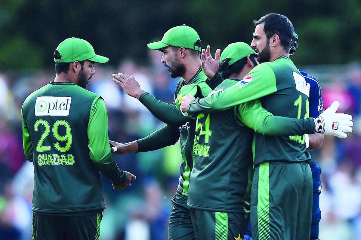 Pakistan's Sarfraz Ahmed (2R) celebrates with Pakistan's Shoaib Malik (R) and Pakistan's Shadab Khan (L) following the first Twenty20 International cricket match between Scotland and Pakistan at the Grange Cricket Club in Edinburgh, Scotland, on June 12, 