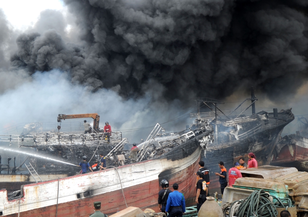Indonesia worker and firefighters try to extinguish a fire on fishing boats at Benoa harbour in Denpasar, on Indonesia's resort island of Bali on July 9, 2018. AFP / Sonny Tumbelaka 