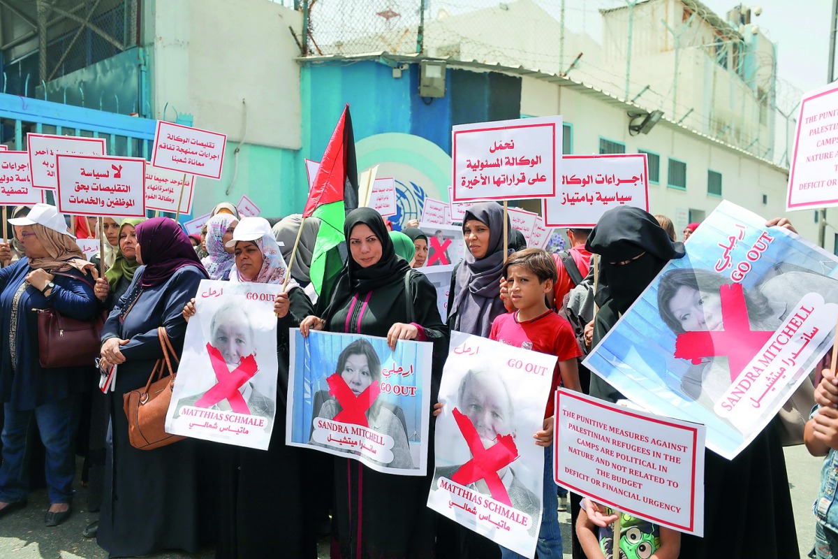 Employees of the UN Relief and Works Agency for Palestinian Refugees (UNRWA) hold UNRWA officials' photos as they gather in front of the UNRWA's headquarters in Gaza City to protest against the agency's recent decision to scale down its operations -- and 