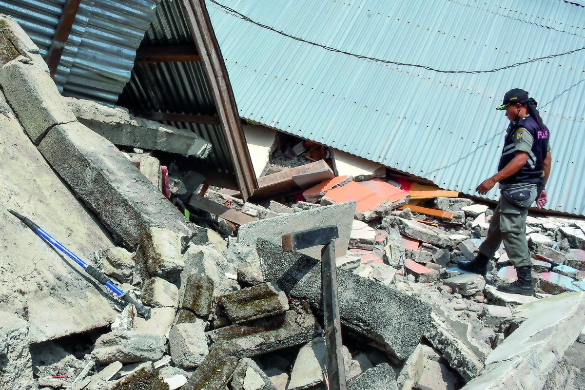 This picture taken on July 29, 2018 shows an Indonesian village security officer examining the debris of houses, after a 6.4 magnitude earthquake struck, in Lombok. AFP / Aulia Ahmad
