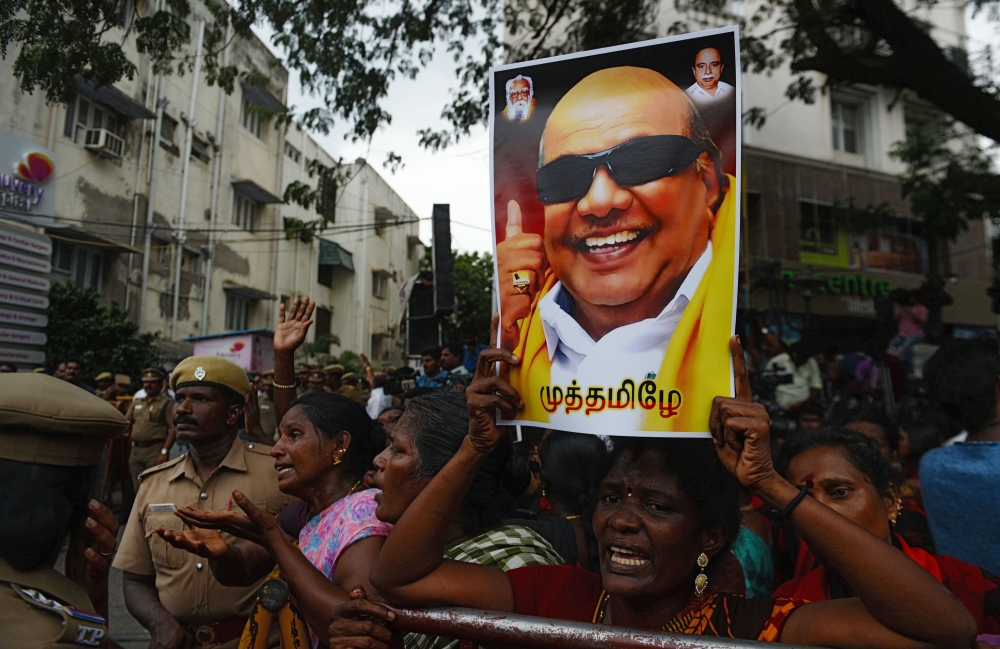 A Dravida Munnetra Kazhagam (DMK) party supporter holds a portrait of party president M. Karunanidhi (R) in front of hospital where he died, in Chennai on August 7, 2018. (AFP / ARUN SANKAR)
