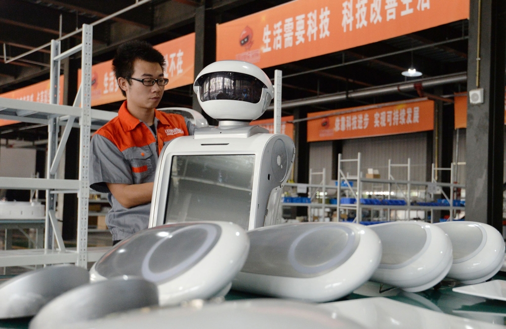 An employee assembles a robot at a factory in Handan in China's northern Hebei province on August 27, 2018. The company provides personalized robots used for customer services. AFP 

 