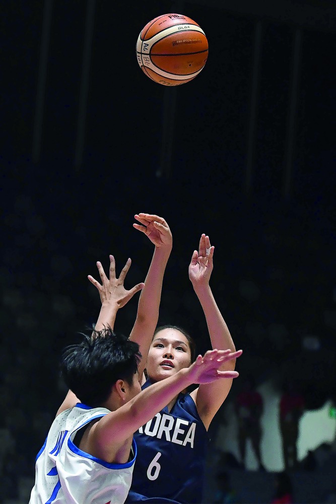 Unified Korea's Choi Eunsil (L) shoots over Taiwan's Wu Yingchieh (C) in the women's basketball semi-final match between Taiwan and Unified Korea during the 2018 Asian Games in Jakarta on August 30, 2018. AFP / Lillian Suwanrumpha
