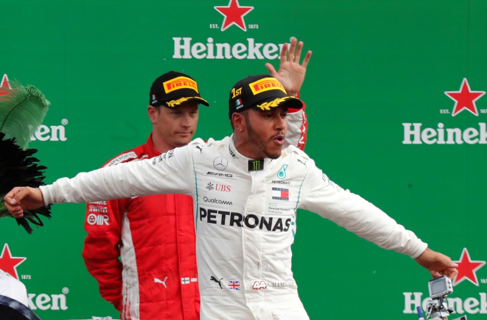 Mercedes' Lewis Hamilton celebrates on the podium after winning the race as Ferrari's Kimi Raikkonen waves to the crowd REUTERS/Stefano Rellandini
