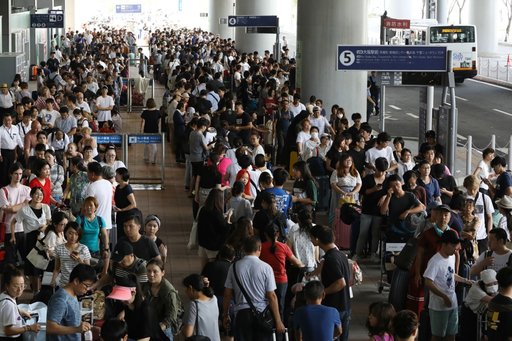 Passengers stranded overnight at the Kansai International Airport due to typhoon Jebi queue for buses that will transport them from the airport in Izumisano city, Osaka prefecture on September 5, 2018. AFP / JIJI PRESS / JIJI PRESS