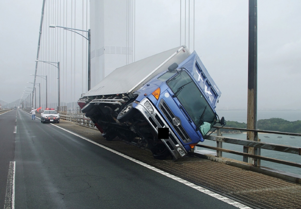 A truck sitting at an angle after being blown over by strong winds caused by Typhoon Jebi on the Seto Ohashi bridge in Sakade, Kagawa prefecture on Japan's Shikoku island.   AFP PHOTO 
