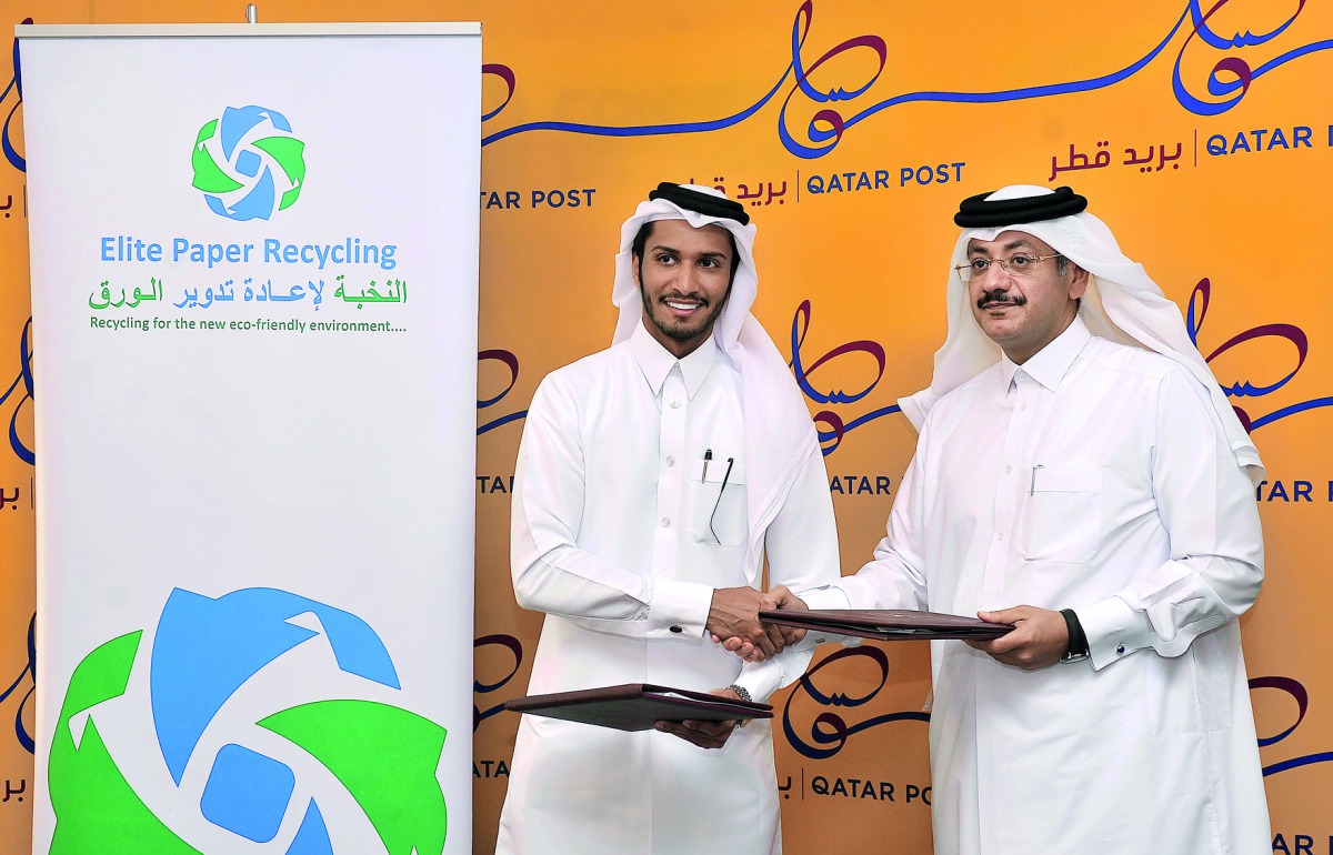 Abdullah Ibrahim Al Suwaidi (left), Chairman Elite Paper Recycling Company and Faleh bin Mohammed Al Naeimi, Chairman and Managing Director of Qatar Post, exchanging the documents after signing the cooperation agreement at Qatar Post headquarters in Doha,