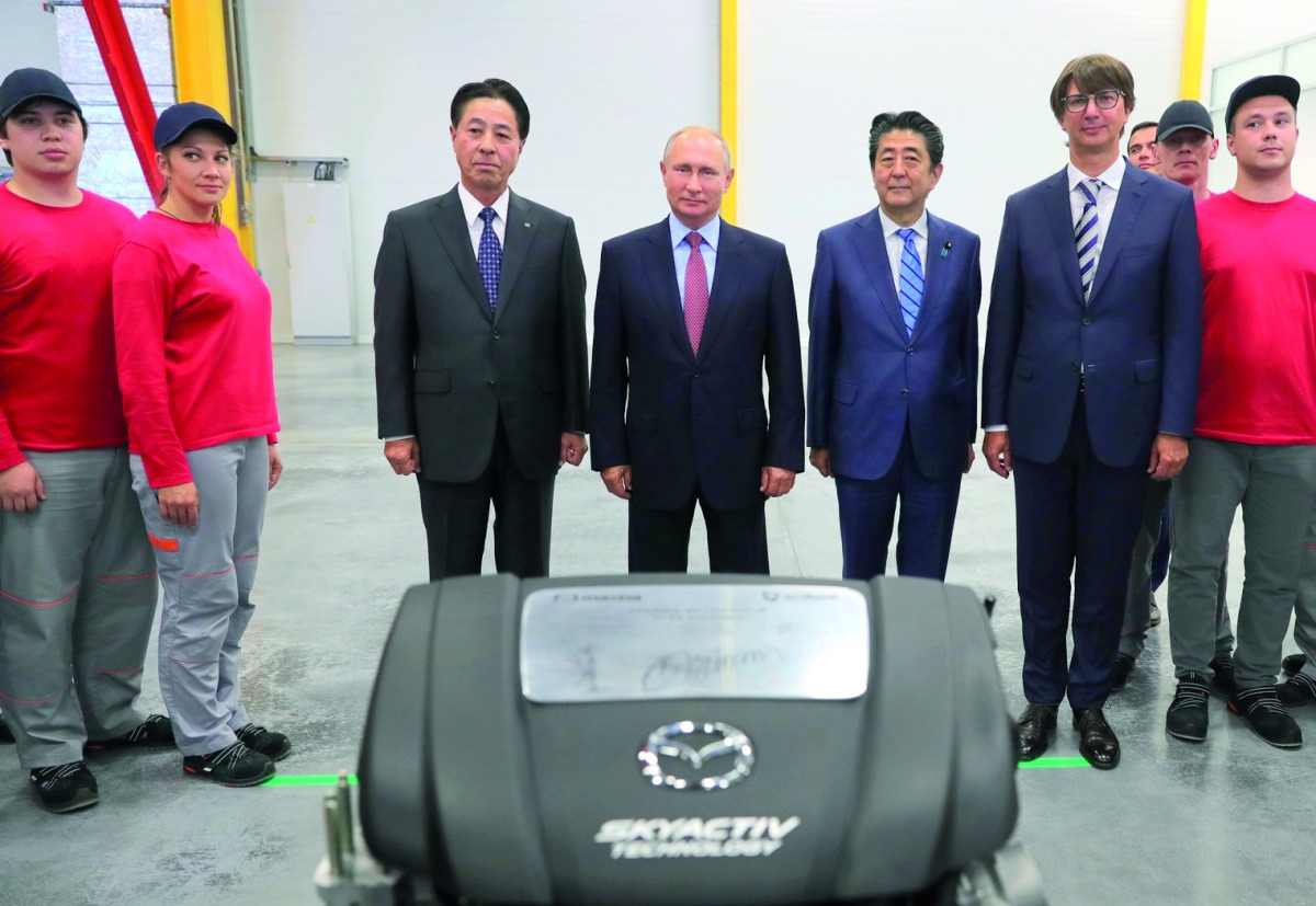 Representative Director and Chairman of the Board at Mazda Motor Corporation Masamichi Kogai (3rd L), Russia's President Vladimir Putin (4th L), Japan's Prime Minister Shinzo Abe (3rd R), Sollers Director General Vadim Shvetsov (2nd R) and workers pose fo