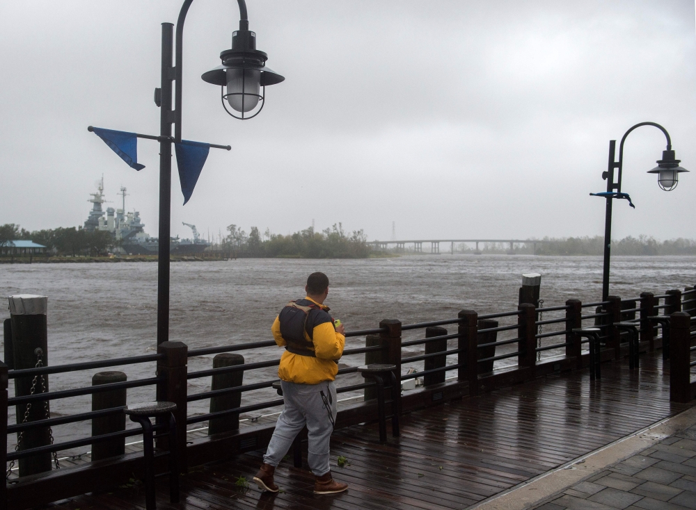 A man walks along the river front as heavy rain from Hurricane Florence falls in Wilmington, North Carolina on September 14, 2018. AFP / Andrew Caballero-Reynolds