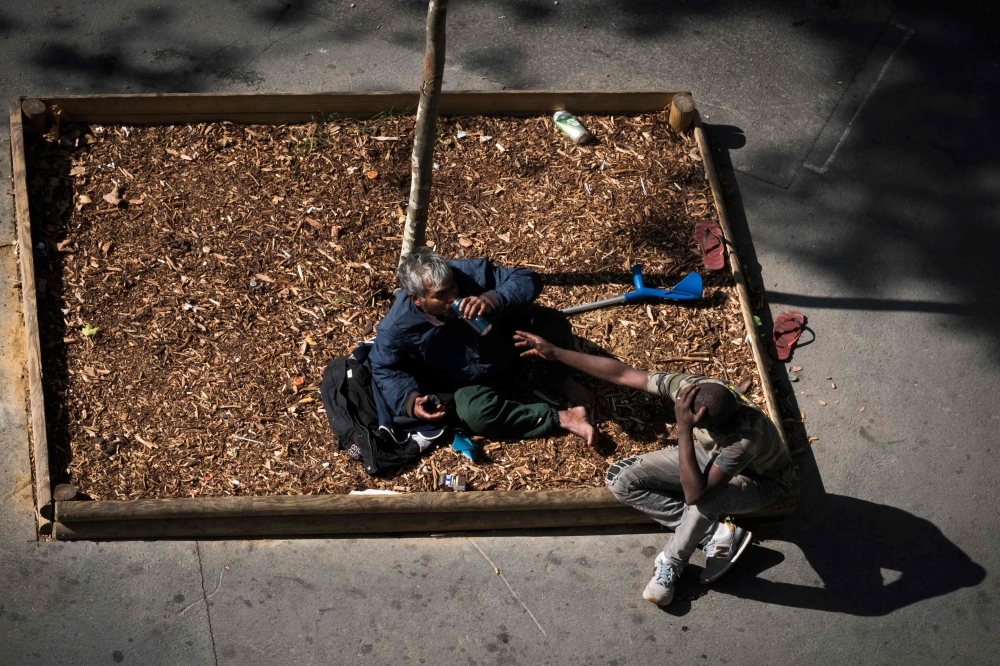 Two homeless men on the pavement in Paris on September 14, 2018. AFP / Joel Saget 