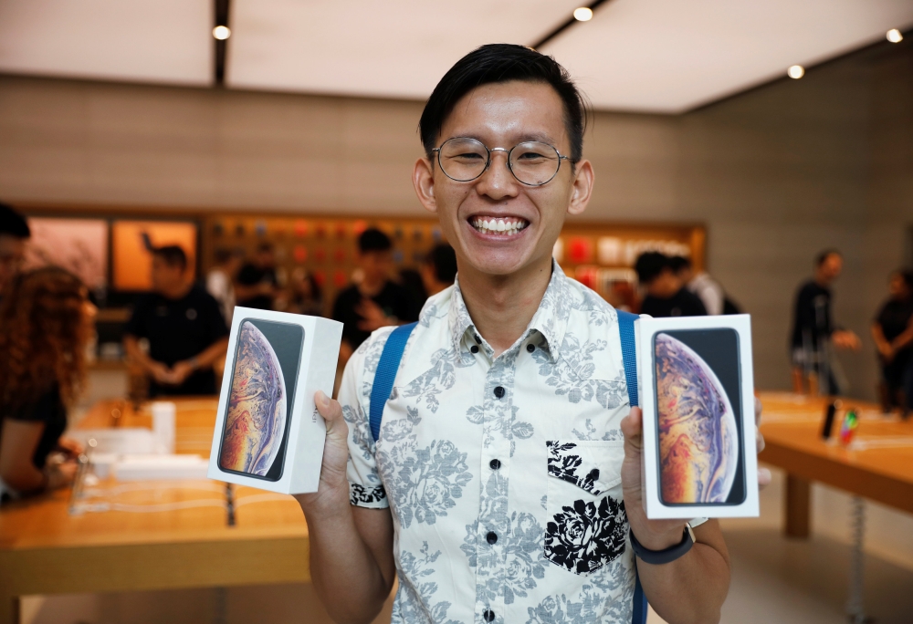 Singaporean Daniel Lim, 23, the first in line to buy the newly released iPhones, poses with his purchases at the Apple Store in Singapore September 21, 2018. Reuters/Edgar Su