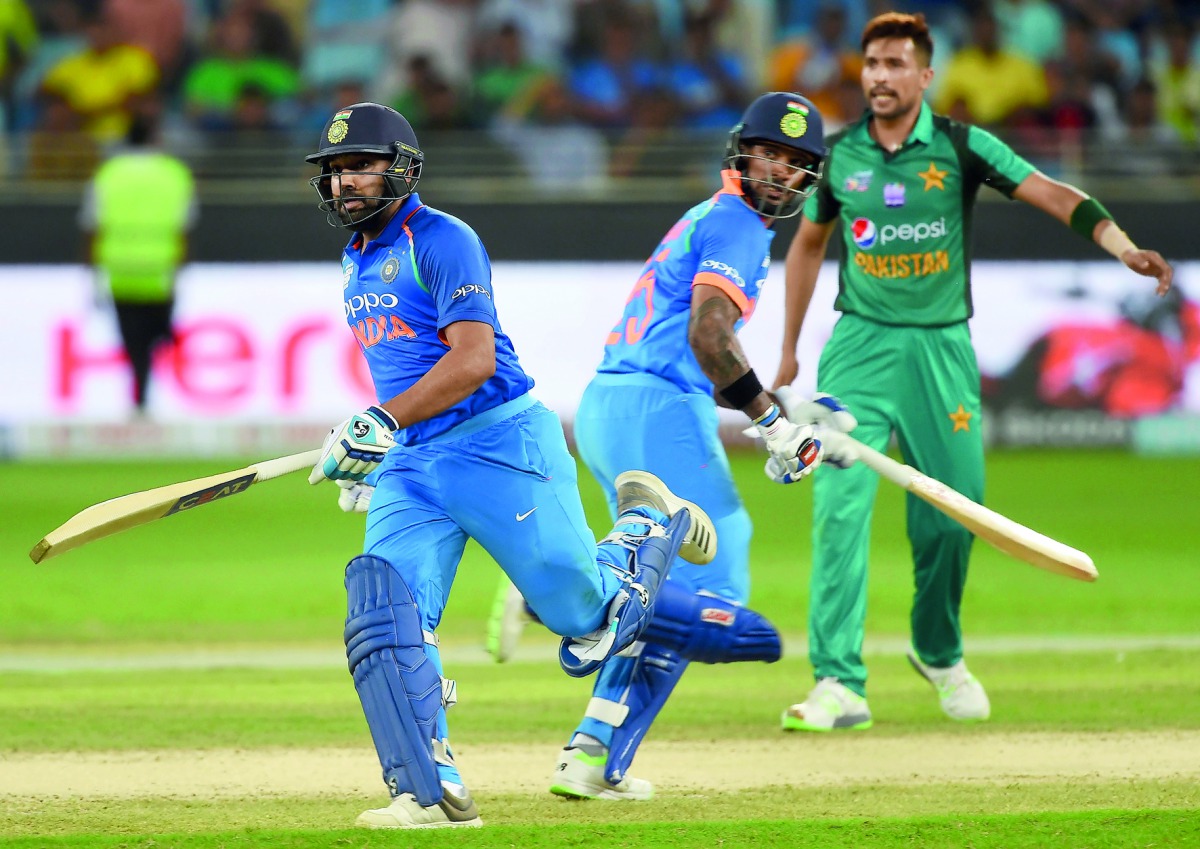 Indian cricket team captain Rohit Sharma (L) and his teammate Shikhar Dhawan (C) run between the wickets during the one day international (ODI) Asia Cup cricket match between Pakistan and India at the Dubai International Cricket Stadium in Dubai on Septem
