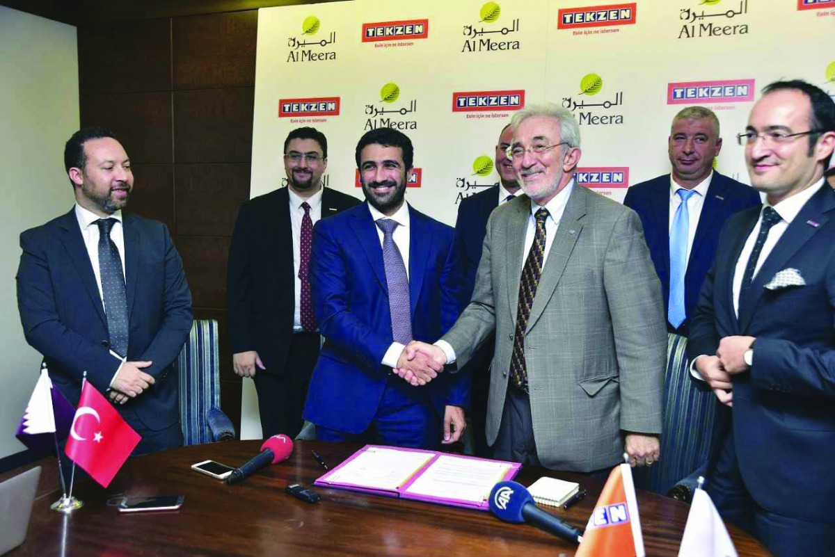 Salah Al Hammadi (third left), Deputy Chief Executive Officer of Al Meera Consumer Goods Company, shakes hands with  Murat Gigin (third right), Chairman of Tekzen, a Turkish Corporation and part of Tekfen Group,as other officials look on, after signing an