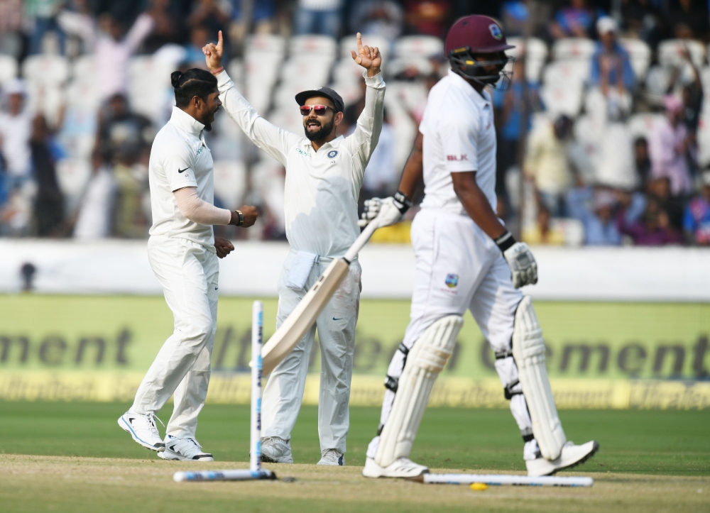 Indian captain Virat Kohli (C) and bowler Umesh Yadav celebrate the dismissal of West Indies batsman Shannon Gabriel (R) during the third day's play of the second Test cricket match between India and West Indies at the Rajiv Gandhi International Cricket S