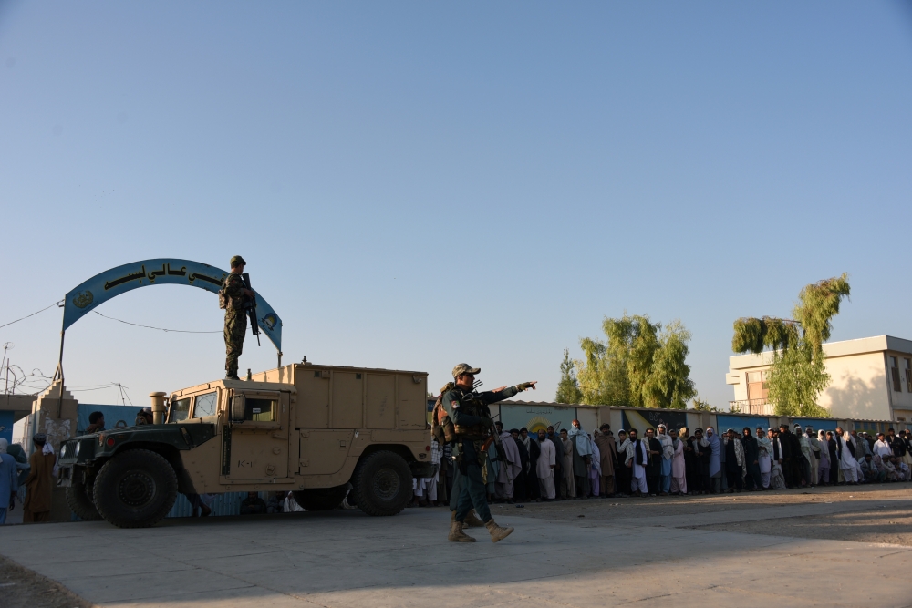 Afghan policemen stand guard as voters wait to cast their votes at a polling centre for the country's legislative election in Kandahar on October 27, 2018. AFP / JAWED TANVEER
 