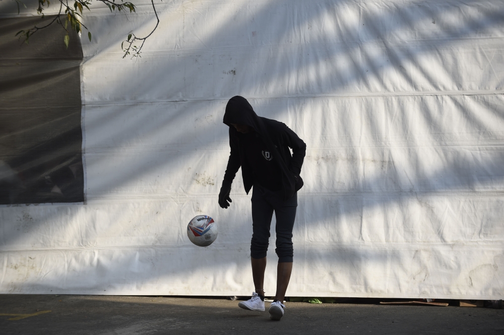 A Central American migrant taking part in a caravan towards the US, plays with a ball at a stadium-turned-shelter during a stop in the journey, in Mexico City on November 7, 2018.  AFP / Alfredo Estrella 

 