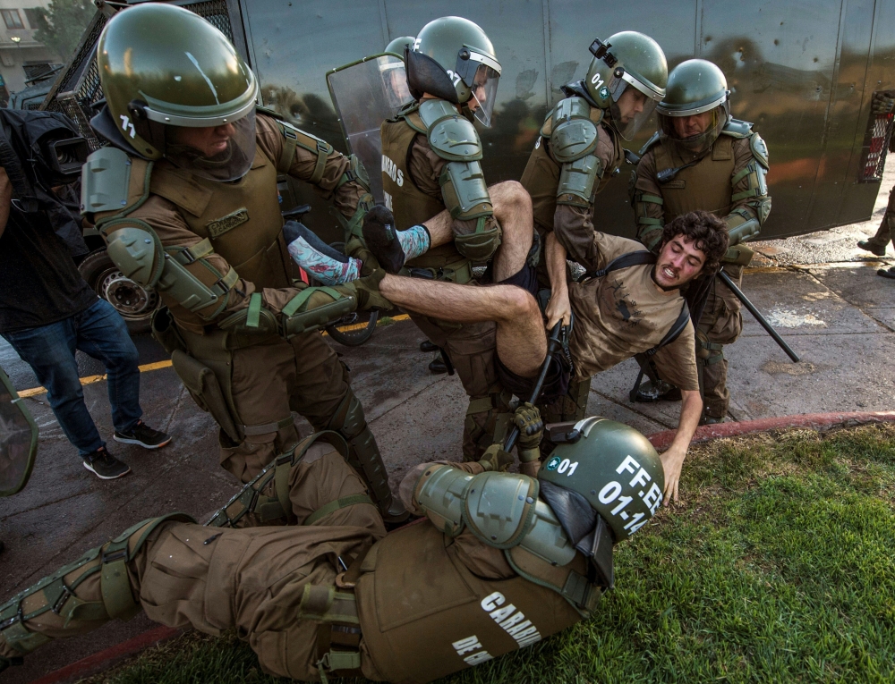 A demonstrator is arrested by riot police during a protest for the death of Mapuche Camilo Catrillanca in Santiago, on November 15, 2018.  AFP / Martin Bernetti 