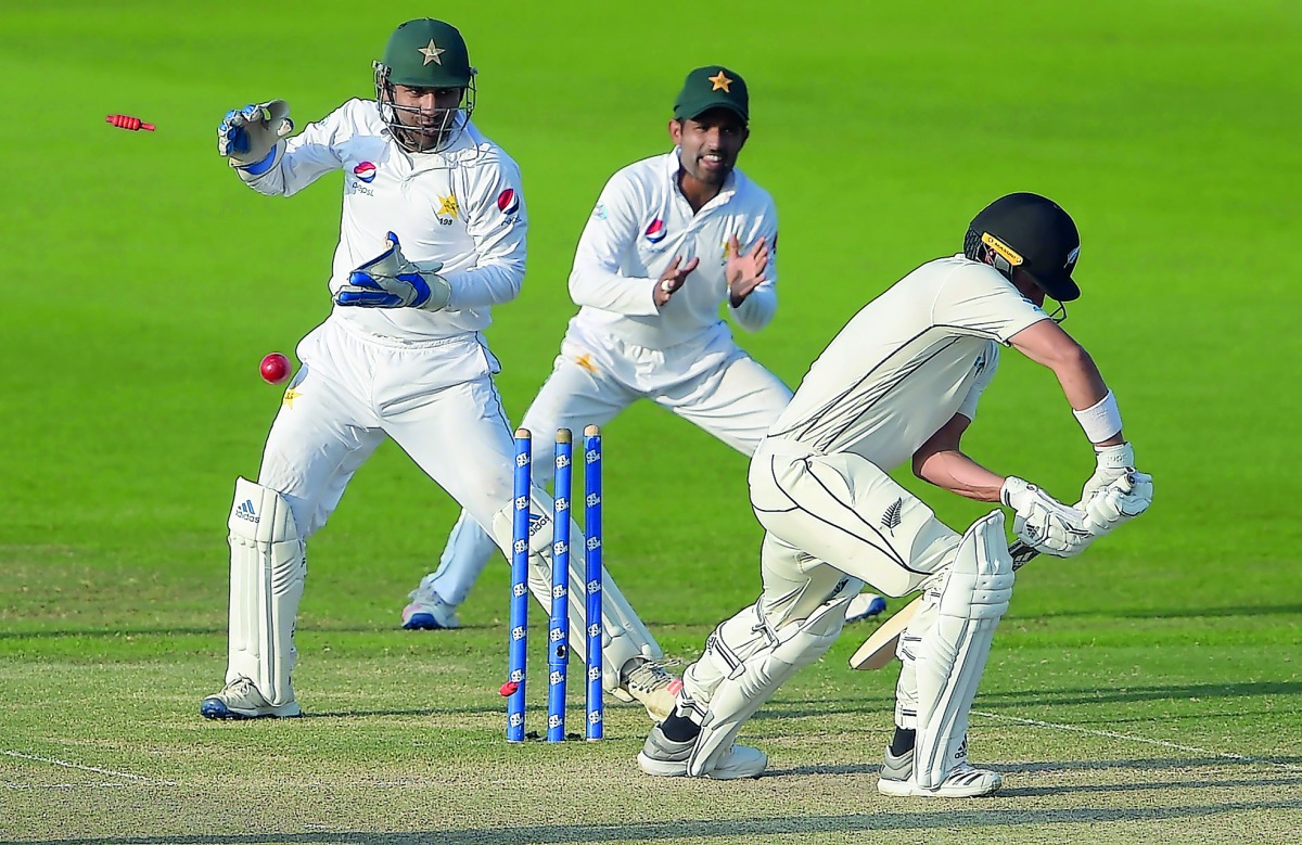 New Zealand batsman Neil Wagner (R) is bowled out as Pakistani captain and wicketkeeper Sarfraz Ahmed (L) and Asad Shafiq (C) look on during the third day of the first Test cricket match between Pakistan and New Zealand at the Sheikh Zayed International C
