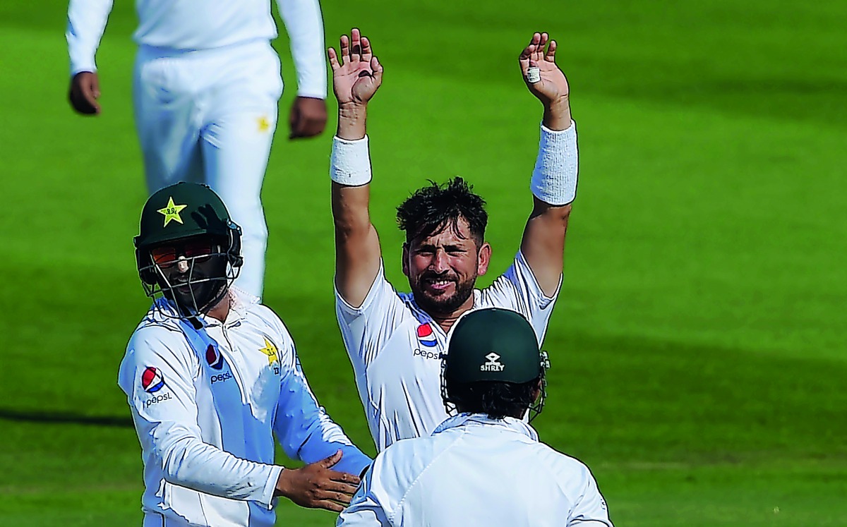 Pakistani spinner Yasir Shah (C) celebrates with teammates after breaking the fastest to 200 Test wickets record during the fourth day of the third and final Test cricket match between Pakistan and New Zealand at the Sheikh Zayed International Cricket Sta