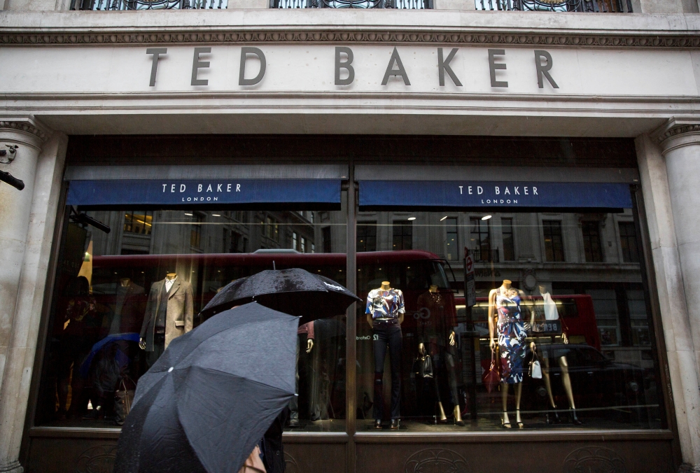 People shelter under umbrellas as they pass a Ted Baker a store in London, Britain October 06, 2015. Reuters/Neil Hall
 