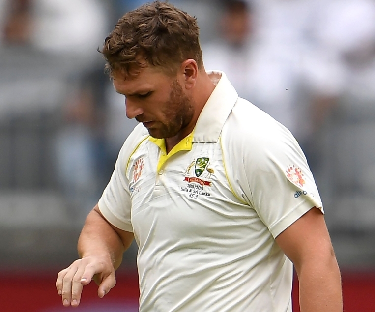 Australia's batsman Aaron Finch has his injured finger inspected after being struck by an Indian delivery on the third day of the second cricket Test match in Perth on December 16, 2018. AFP / WILLIAM WEST