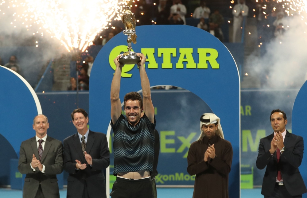 Spain's Roberto Bautista Agut (front) raises the trophy after winning against Czech Republic's Tomas Berdych the ATP Qatar Open tennis final match in Doha on January 5, 2019. / AFP / KARIM JAAFAR