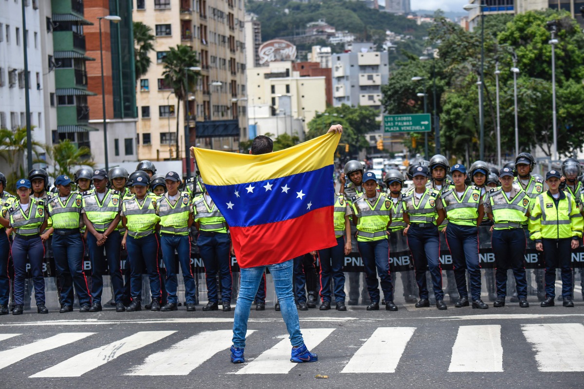 A member of the Venezuela opposition gestures showing a national flag in front of policemen during a demonstration in Caracas on July 27, 2016. (AFP) 