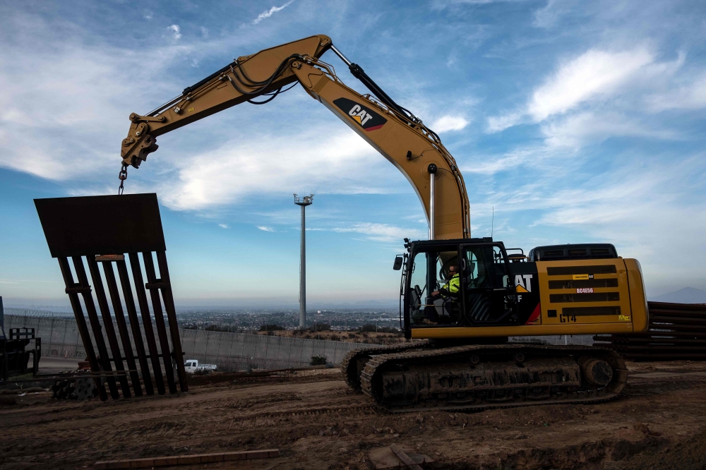 A construction crew works on replacing the US-Mexico border fence as seen from Tijuana, in Baja California state, Mexico, on January 9, 2019.  AFP / Guillermo Arias
 