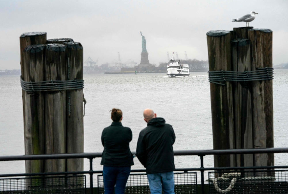 People watch as the Statue of Liberty and Ellis Island ferry transports passengers in New York in this file photo taken on January 5, 2019, as the US government shutdown enters its third week, but New York funds are keeping the Ellis Island and Liberty Pa