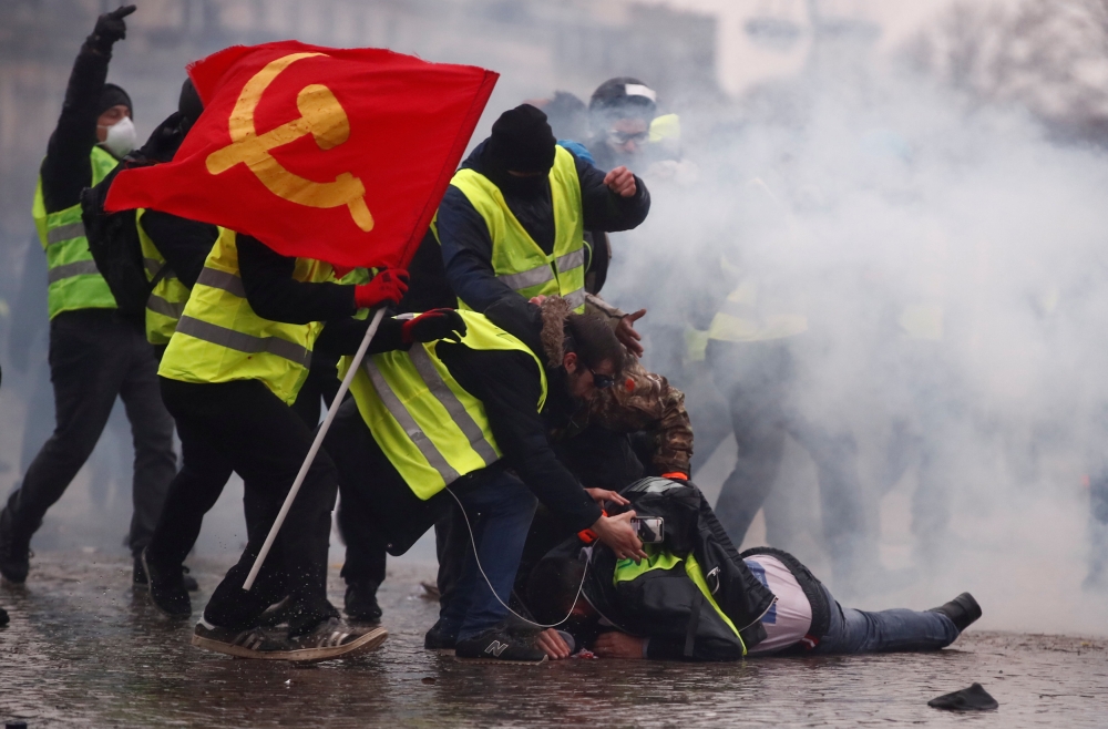 Protesters wearing yellow vests help a person injured by a water cannon during a demonstration by the 