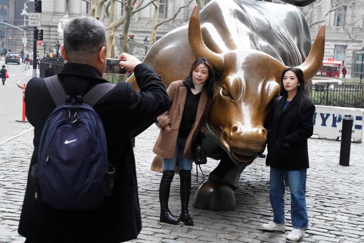 People pose for photos with the Charging Bull or Wall Street Bull in the Manhattan borough of New York City,  January 16, 2019. Reuters/Carlo Allegri