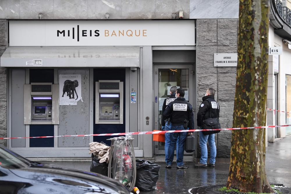 French police check the entrance to the Milleis Banque close to the Champs-Elysees Avenue in central Paris on January 22, 2019, following a robbery earlier in the day. Criminals entered the bank holding people on the premises hostage for several hours as 
