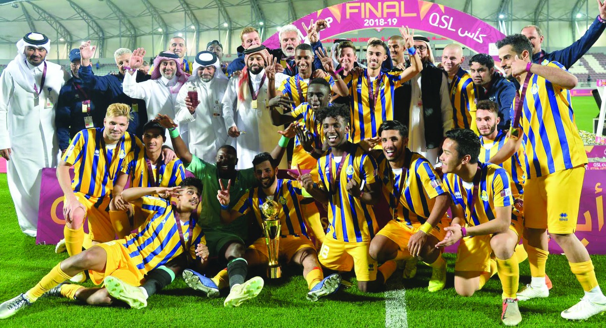 Al Gharafa’s players and officials celebrate with the QSL Cup after winning the final against Al Duhail yesterday. 
