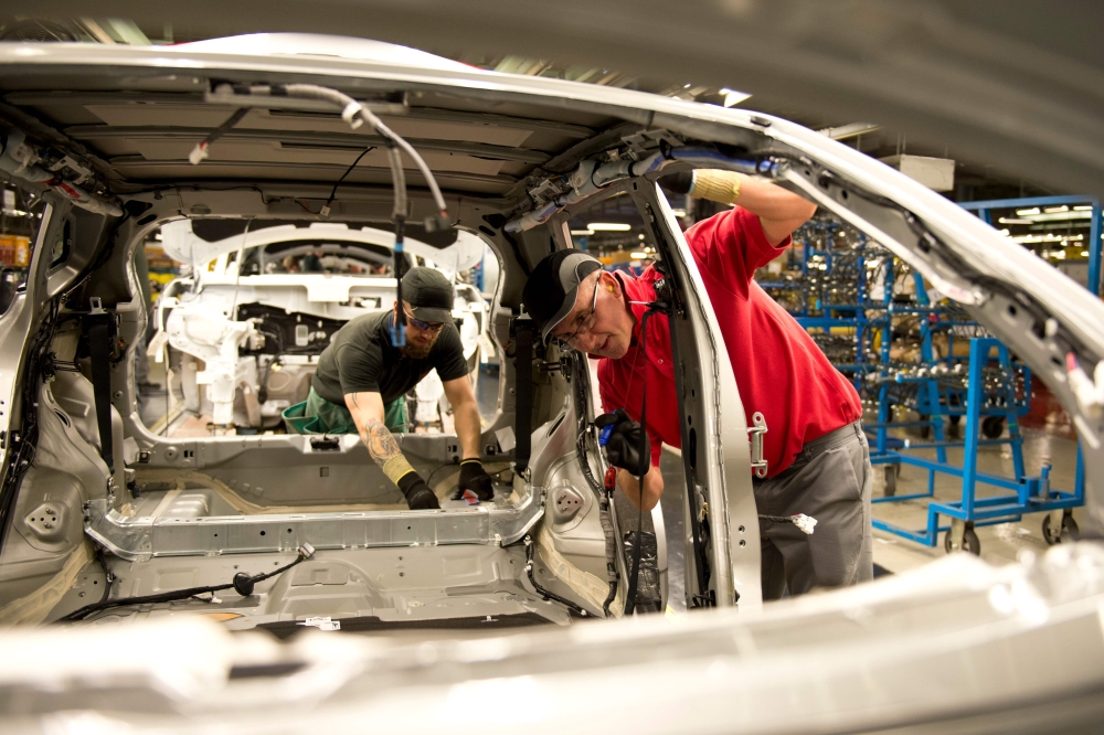 A 'Check and Repair' member of Nissan's manufacturing staff (R) works in the 'Trim and Chassis' section of their Sunderland Plant in Sunderland, North East England on November 12, 2014.  AFP / Oli Scarff