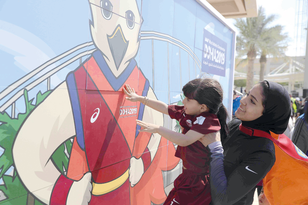 Qatari athlete Mariam Farid assists a young kid to fix a piece of the jigsaw puzzle that has the picture of Falah - the official mascot of the Doha 2019 World Athletics Championship, during the unveiling ceremony at Qatar Foundation’s Awsaj Academy, yeste