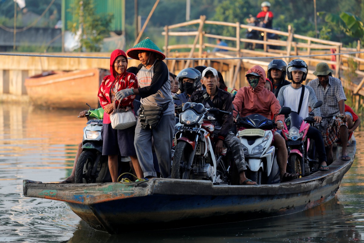 Motorists are being transported on a raft as they cross a river in Jakarta, Indonesia, February 14, 2019. Reuters/Willy Kurniawan