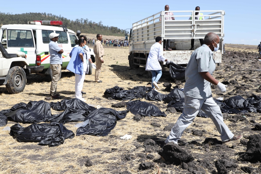 Rescue team walk past collected bodies in bags at the crash site of Ethiopia Airlines near Bishoftu, a town some 60 kilometres southeast of Addis Ababa, Ethiopia, on March 10, 2019.  AFP / Michael Tewelde 